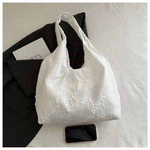 Gros plan d'un sac cabas en toile blanche avec broderies florales 3D et dentelle épurée