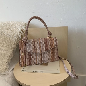 Detail of striped woven straw handbag with wood furniture and aesthetic decor