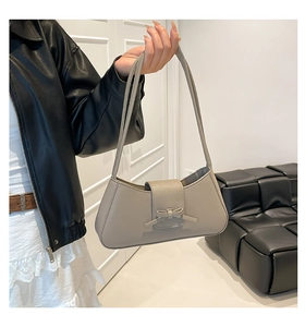 Detalle del bolso de hombro gris con decoración de lazo y textura de cuero granulado