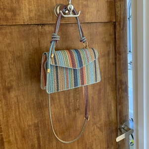 Detail of multi-colored striped woven shoulder bag with gold hardware and chain strap