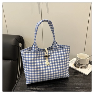 Dettaglio borsa tote in tela a quadretti blu con chiusura a fune in cotone e bottone in corno