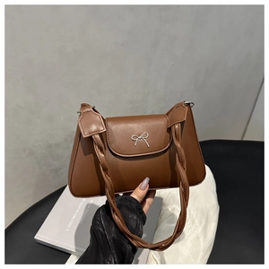 Detail of vintage brown leather handbag with woven handle and silver bow buckle closure