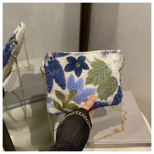 Détail de la broderie florale avec paillettes sur un petit sac à bandoulière tissé
