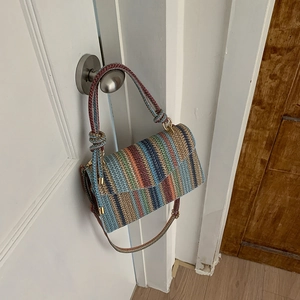 Detail of colorful striped woven shoulder bag featuring golden metal buckles and texture