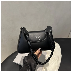 Close-up of black underarm bag with silver bow detail and twisted shoulder strap