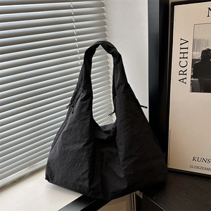 Large black drawstring tote bag in crinkled nylon fabric with a minimalist urban aesthetic