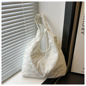 Détail du sac à bandoulière blanc avec broderies florales jaunes et texture en tissu doux