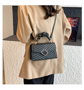 Detail of black quilted shoulder bag with ruched handle and metallic clasp closure