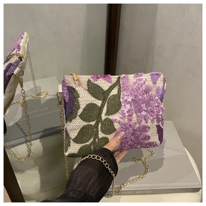 Détails de broderie florale et de paillettes violettes sur un sac à chaîne blanc cassé