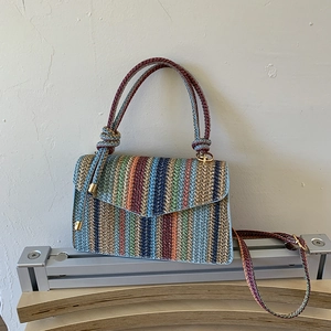 Detail of multi-color striped woven crossbody bag with golden hardware and long strap