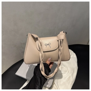 Detail of beige faux leather shoulder bag with silver bow clasp and twisted strap
