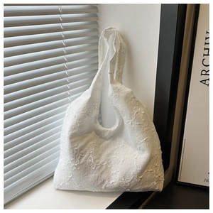 Détail de broderie florale blanche sur un sac fourre-tout en coton au design minimaliste