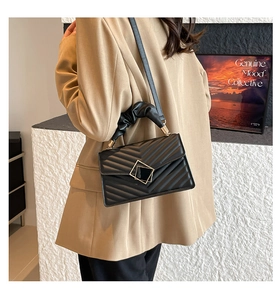 Detail of black quilted handbag with gold square clasp and ruched cloud handle