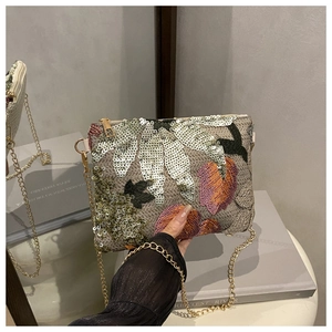 Détail d'un petit sac carré brodé de paillettes avec une bandoulière dorée