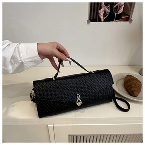 Dettaglio borsa nera a trama intrecciata con chiusura a rotazione in metallo dorato