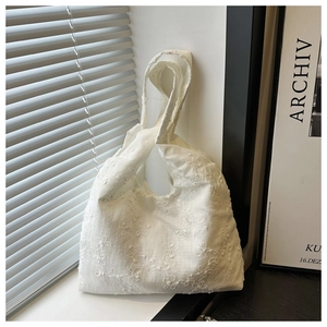 Gros plan de broderies florales blanches sur le tissu en coton d'un sac à main chic