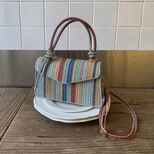 Close-up of a colorful striped woven handbag featuring golden buckles and fine knit texture
