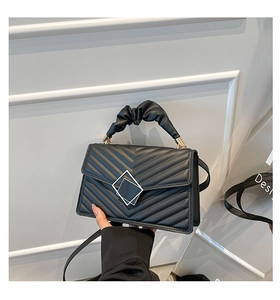 Close-up of black chevron quilted crossbody bag with gold buckle and ruched handle