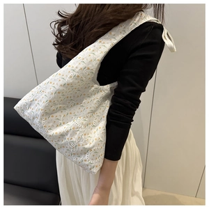 Détail du sac cabas blanc avec broderie florale jaune et texture ajourée élégante