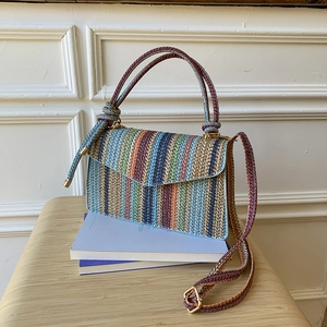 Macro detail of multi-colored striped woven shoulder bag with gold-tone metal hardware