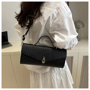 Dettaglio di una borsa nera con trama a coccodrillo e fibbia in metallo distintiva