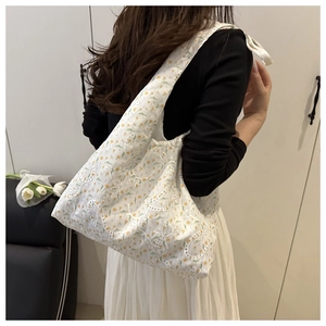 Vue détaillée d'un sac cabas blanc avec broderies de fleurs jaunes et motifs ondulés