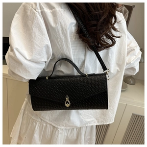 Vista dettagliata di una borsa baguette nera intrecciata indossata da una modella