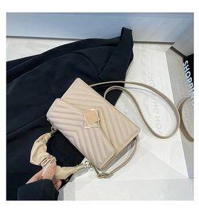 Detail of beige chevron quilted crossbody bag with stylish pleated handle and metal buckle