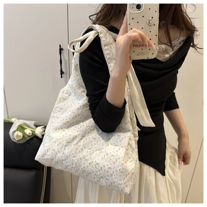 Close-up of white floral embroidery and delicate lace texture on canvas tote bag