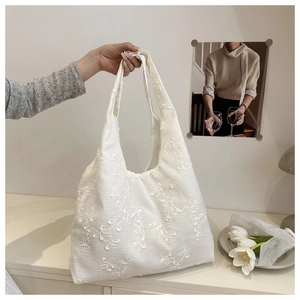 Gros plan sur la broderie florale blanche d'un sac cabas en tissu aux textures douces