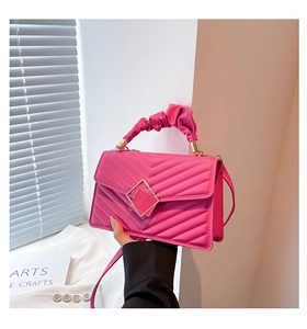 Detail of rose red crossbody bag featuring V-shaped chevron quilting and pleated handle