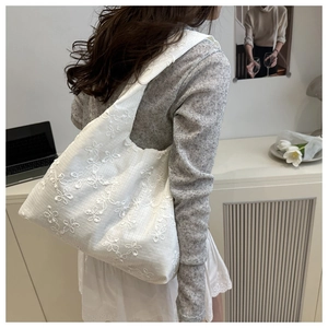 Detailed close-up of white 3D floral embroidery on a large capacity shoulder bag