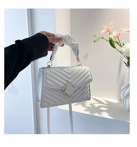 Close-up of white quilted handbag with V-stitch patterns and ruched handle detail
