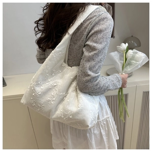 Détail de broderie florale en dentelle blanche sur un grand sac cabas en toile
