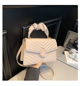 Close-up of V-shaped quilted beige leather bag with pleated handle and gold hardware
