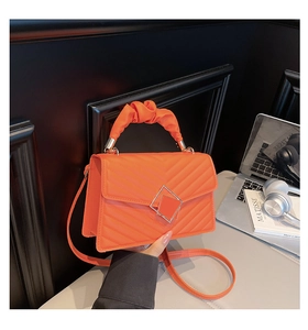 Detail of orange quilted square bag with V-pattern stitching and metal buckle clasp