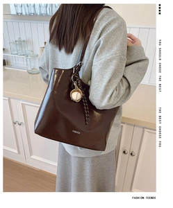 Detail of dark brown glossy tote bag with baseball pendant and Fashion text logo