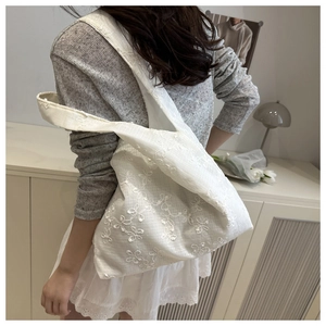 Détail de la broderie florale blanche sur un sac fourre-tout en dentelle minimaliste
