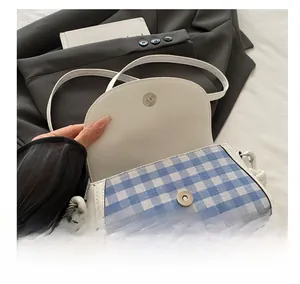 Détail du sac à bandoulière à carreaux bleus montrant le bouton pression magnétique en métal