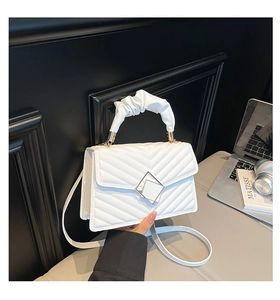 Detail of white quilted handbag with pleated handle and square metal buckle closure