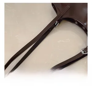 Close-up of adjustable shoulder strap with silver buckle on dark brown oily leather tote bag