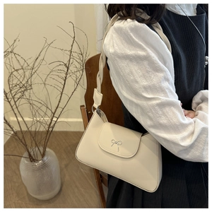 Detail of cream leather shoulder bag with silver bow buckle and ruched strap design