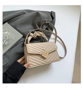 Close-up of beige quilted bag with golden geometric lock and ruffled cloud handle
