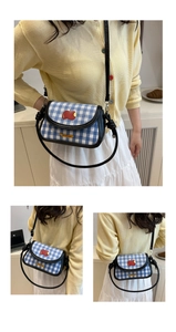 Détail du mini sac selle à carreaux bleu et blanc avec écusson pomme rouge et cuir noir