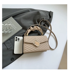 Detailed close-up of a beige chevron quilted handbag with gold geometric buckle and strap