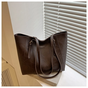 Detail shot of a large brown tote bag with leather grain texture on a window sill