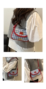 Détail du mini sac selle à carreaux bleus avec broderie pomme rouge et bordure