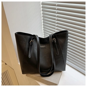 Close-up of black tote bag with lychee texture and gold metal buckle detail