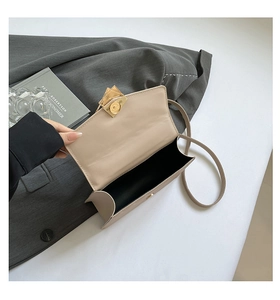 Detail view of beige quilted leather crossbody bag with distinctive gold metal buckle