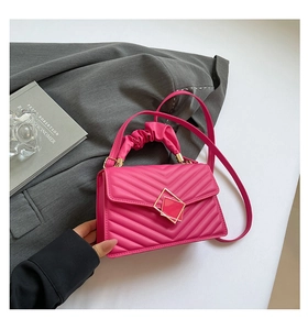 Detail of fuchsia pleated handle bag with chevron quilting and golden buckle